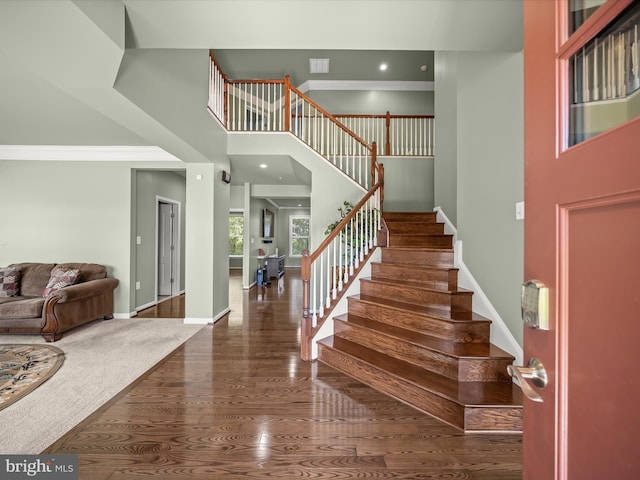 foyer featuring stairs, wood finished floors, a towering ceiling, and baseboards