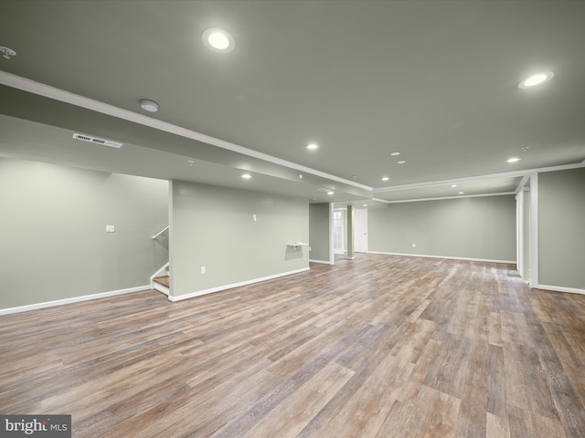 finished below grade area featuring recessed lighting, wood finished floors, stairway, baseboards, and crown molding