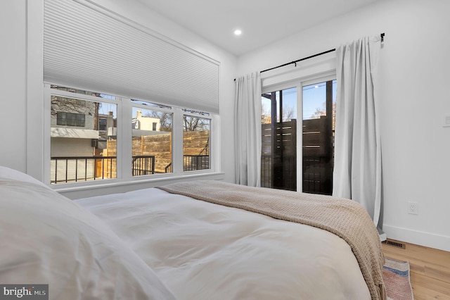 bedroom featuring visible vents, wood finished floors, baseboards, access to outside, and recessed lighting