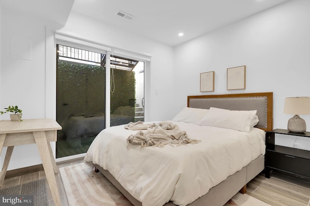 bedroom with access to outside, recessed lighting, wood finished floors, and visible vents