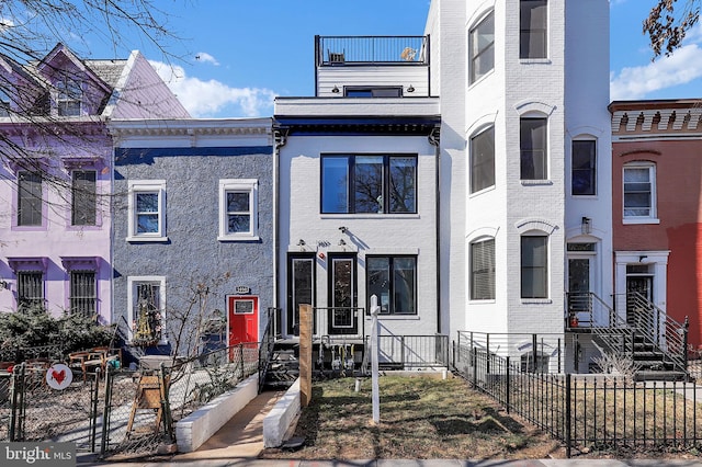 multi unit property with a balcony, a fenced front yard, and brick siding