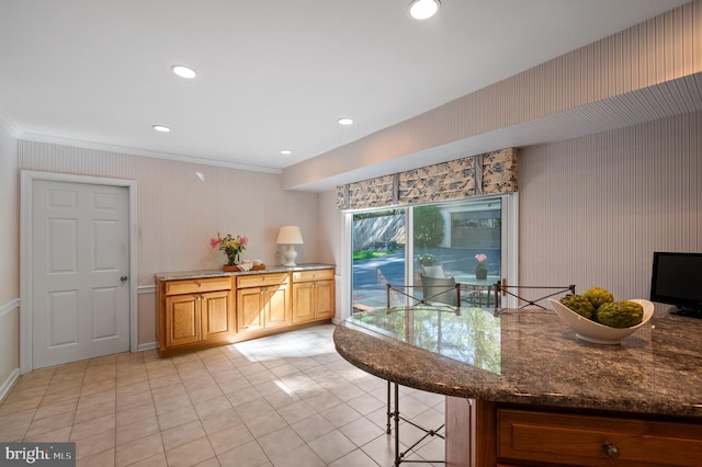 kitchen featuring crown molding, light tile patterned floors, wallpapered walls, dark stone countertops, and recessed lighting