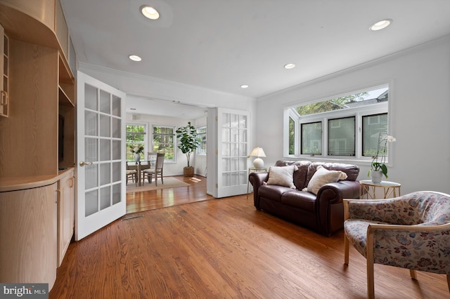 living area featuring french doors, recessed lighting, crown molding, and wood finished floors