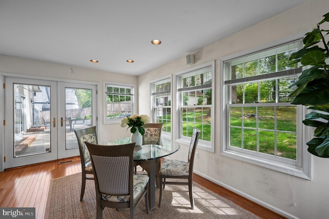 sunroom / solarium featuring french doors, baseboards, plenty of natural light, and hardwood / wood-style flooring