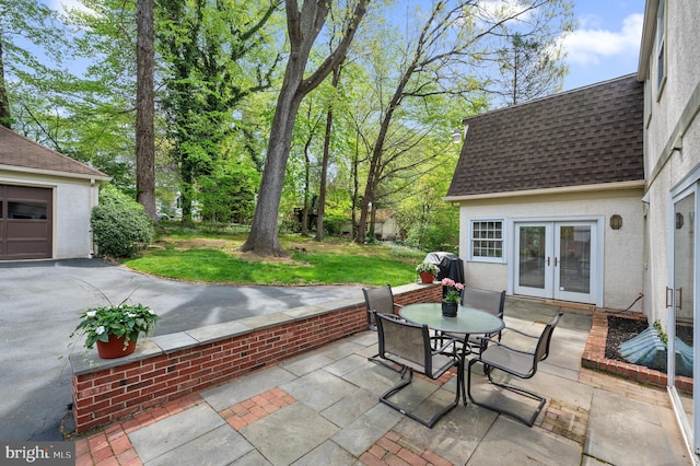 view of patio featuring french doors, driveway, and outdoor dining space