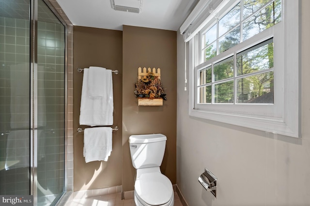 full bathroom featuring baseboards, tile patterned floors, toilet, and tiled shower