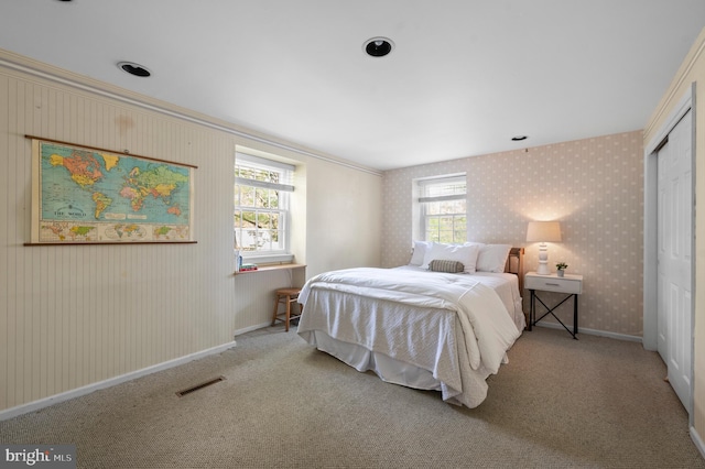 carpeted bedroom featuring baseboards, visible vents, wallpapered walls, and a closet