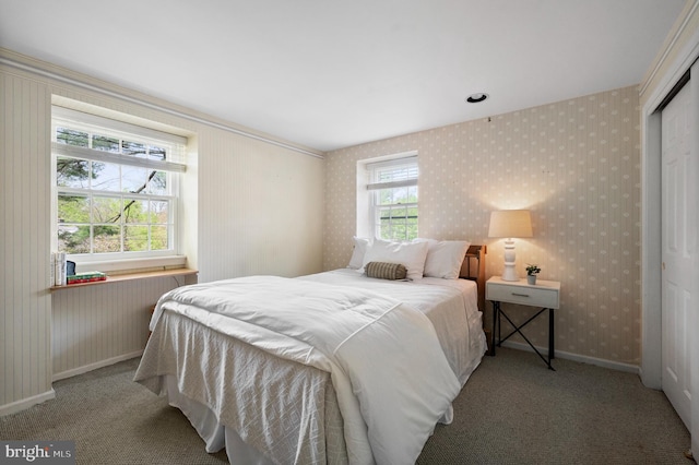 carpeted bedroom featuring wallpapered walls, baseboards, and a closet