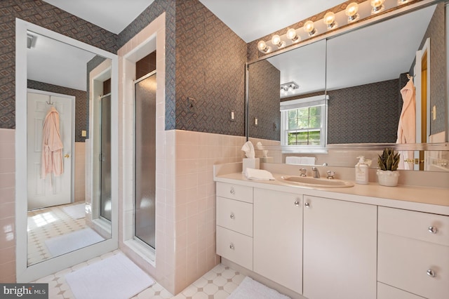 full bath with tile walls, a shower stall, vanity, a wainscoted wall, and tile patterned floors
