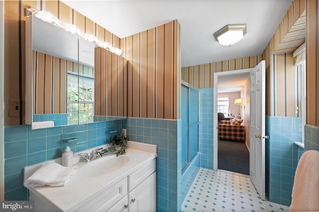 full bath featuring a shower with door, tile walls, a wealth of natural light, and wallpapered walls