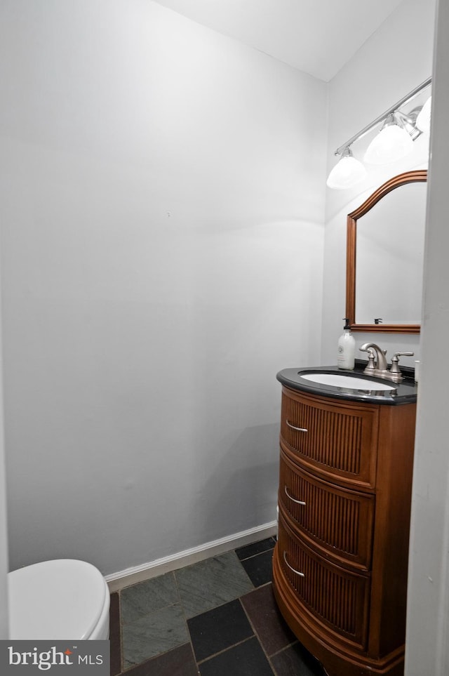 bathroom with vanity, baseboards, and toilet