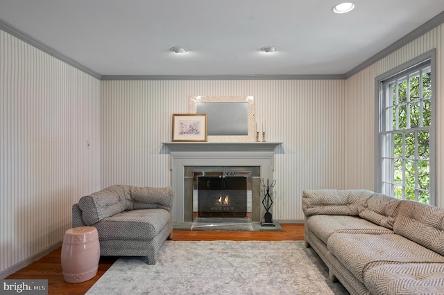 living area featuring crown molding, a lit fireplace, and wood finished floors