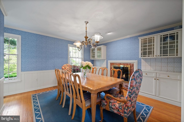 dining space featuring a healthy amount of sunlight, a wainscoted wall, an inviting chandelier, and light wood-type flooring