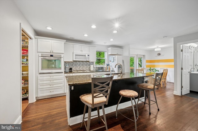 628 Edge Hill Rd, Glenside, PA 19038 - kitchen featuring stainless steel oven, white microwave, gas cooktop, a center island with sink, and refrigerator with ice dispenser