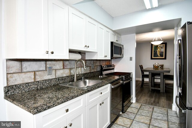 4500 S Four Mile Run Dr Unit 1218, Arlington, VA 22204 - kitchen with dark stone counters, a sink, backsplash, white cabinetry, and appliances with stainless steel finishes