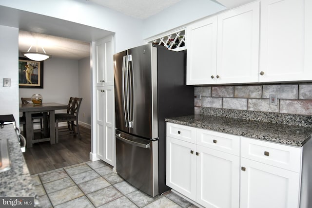4500 S Four Mile Run Dr Unit 1218, Arlington, VA 22204 - kitchen with dark stone countertops, white cabinetry, freestanding refrigerator, and backsplash
