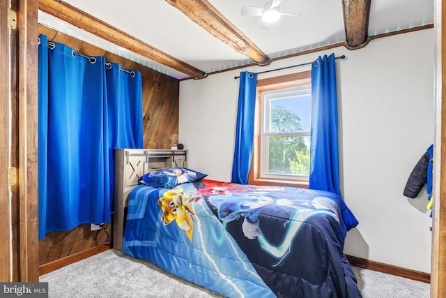 bedroom with carpet flooring, ceiling fan, beam ceiling, wood walls, and baseboards
