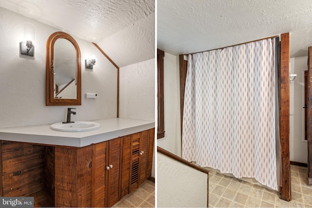 bathroom with vanity, a textured ceiling, and vaulted ceiling