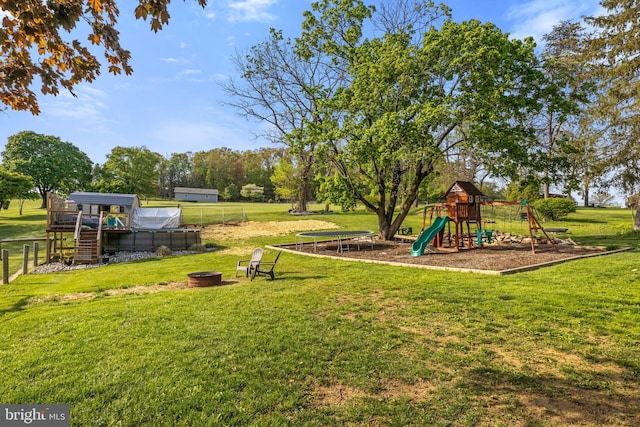 view of yard featuring fence, a greenhouse, and a playground