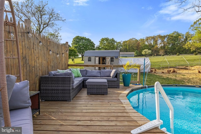 outdoor pool with an outdoor living space, fence, an outbuilding, and a deck