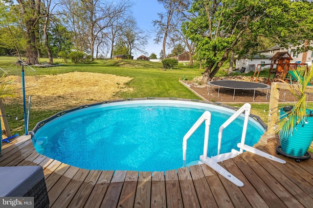 pool with a yard, a playground, a trampoline, and a deck