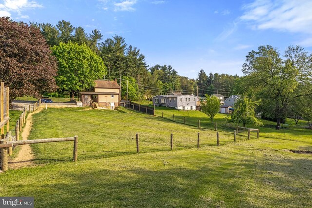 view of yard featuring an outdoor structure, fence, and a rural view