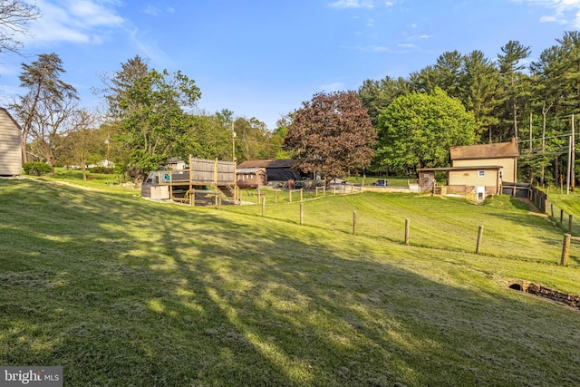view of yard with a deck, fence, and an outbuilding