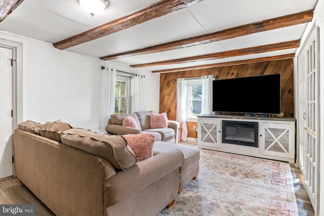 living room featuring beamed ceiling, wood walls, and wood finished floors