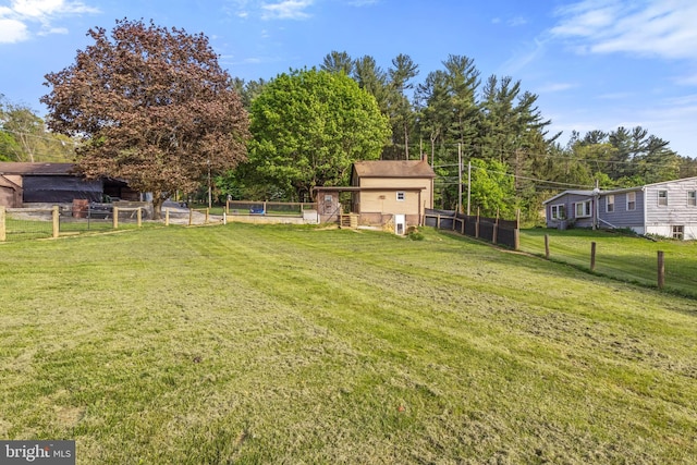 view of yard featuring fence, a storage unit, and an outbuilding
