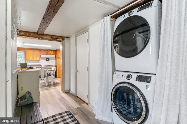 washroom featuring laundry area, stacked washer and clothes dryer, and light wood-style floors