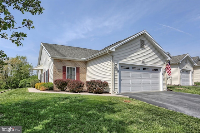 ranch-style house featuring driveway, roof with shingles, a front yard, a garage, and brick siding