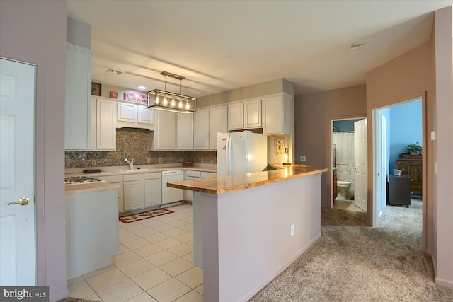 kitchen featuring white cabinets, a sink, white appliances, a peninsula, and backsplash