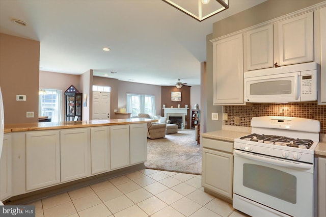 kitchen with a fireplace, white appliances, ceiling fan, light countertops, and light tile patterned floors