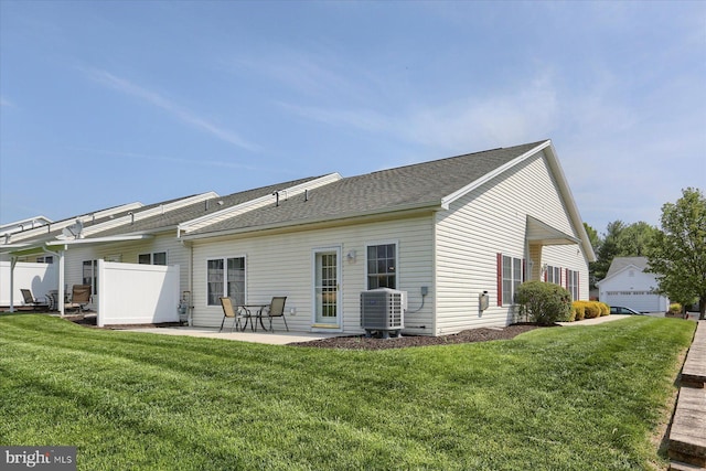 back of house featuring central air condition unit, a patio, a shingled roof, and a lawn