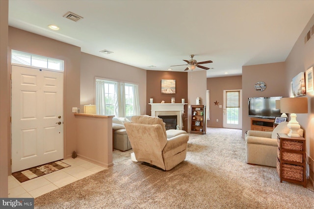 living area with a ceiling fan, visible vents, baseboards, a glass covered fireplace, and carpet