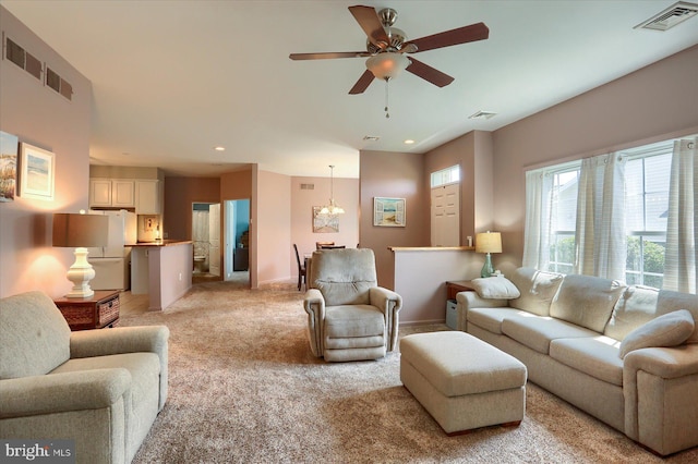 living room featuring visible vents, light carpet, and ceiling fan with notable chandelier