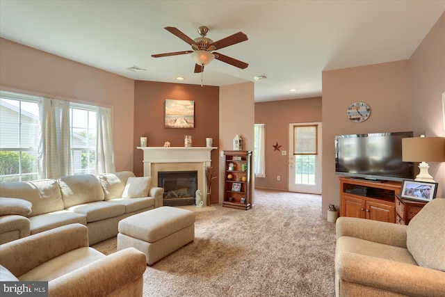 living room with light colored carpet, plenty of natural light, ceiling fan, and visible vents