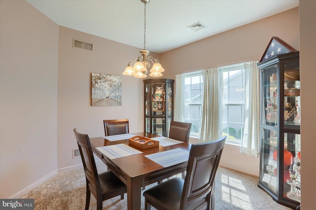 dining room featuring visible vents, a healthy amount of sunlight, a notable chandelier, and light colored carpet