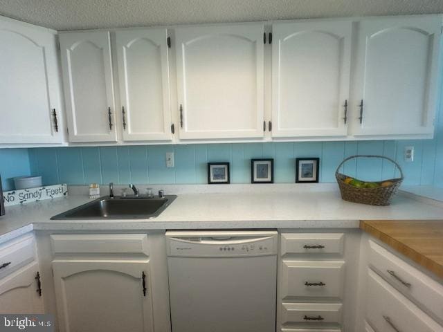 kitchen featuring white cabinets, dishwasher, light countertops, and a sink
