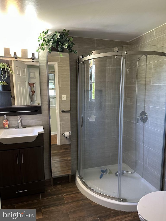 full bath featuring vanity, a shower stall, toilet, and wood finished floors