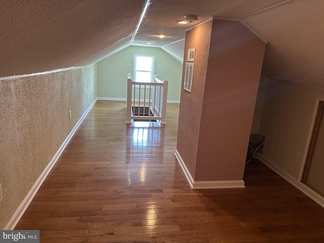 additional living space featuring wood finished floors, baseboards, a textured ceiling, and lofted ceiling