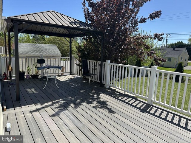 wooden terrace featuring a gazebo, an outbuilding, and a yard