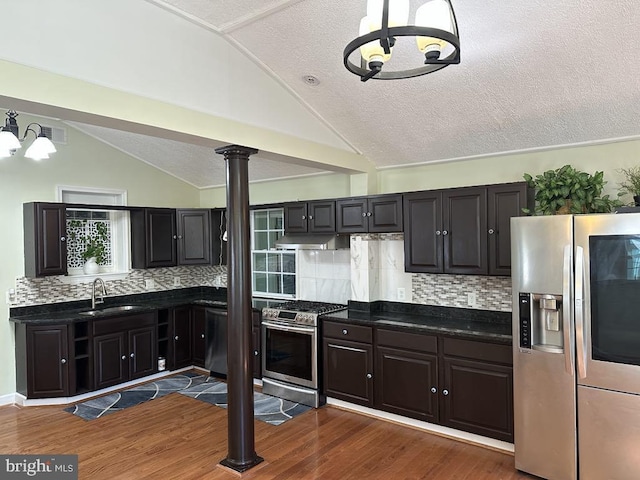 kitchen with a sink, a notable chandelier, vaulted ceiling, and stainless steel appliances