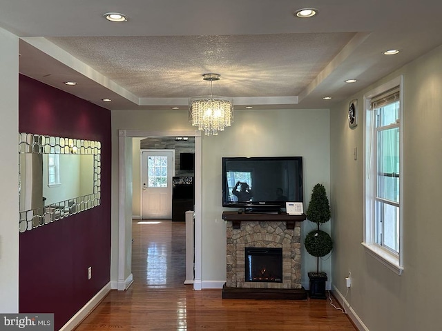 living room with baseboards, a raised ceiling, and a wealth of natural light