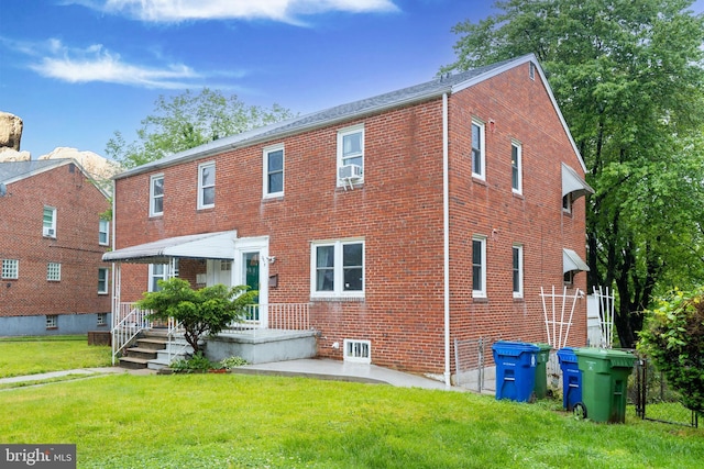 rear view of property featuring a lawn, brick siding, and cooling unit