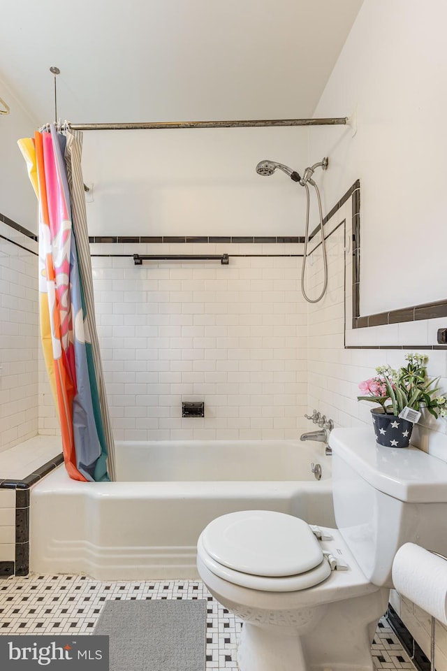full bath with shower / bath combination with curtain, toilet, and tile walls