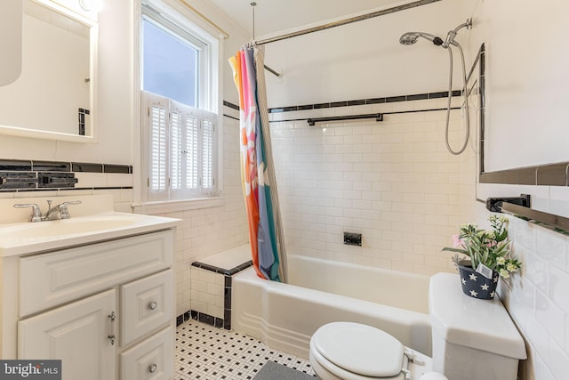 full bath with tile walls, toilet, shower / bath combo, vanity, and wainscoting