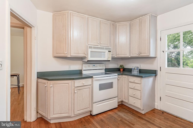 kitchen with white appliances, dark countertops, and light wood-type flooring