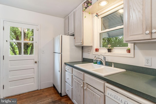 kitchen featuring white appliances, a sink, plenty of natural light, and dark countertops