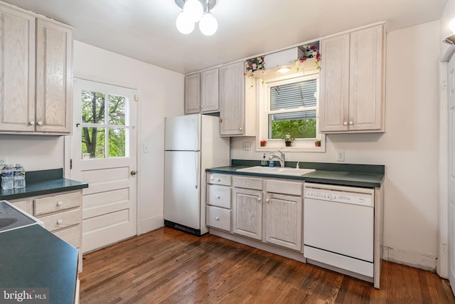 kitchen with white appliances, a sink, dark wood finished floors, and dark countertops